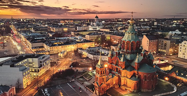 A stunning aerial shot of Helsinki, Finland, showcasing the Uspenski Cathedral and the city's cityscape bathed in the golden light of sunset